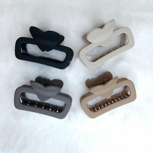 Four hair clips in black, gray, and beige on a white background