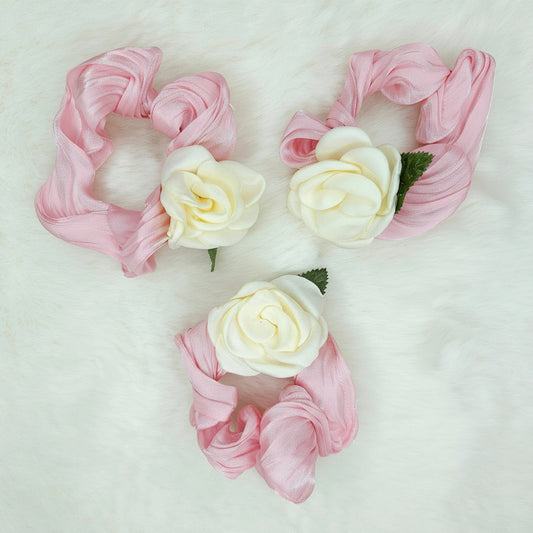 Three pink scrunchies with white flowers on a light gray background