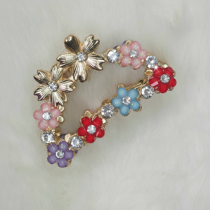 Decorative hair clip with colorful flowers and rhinestones on a light background