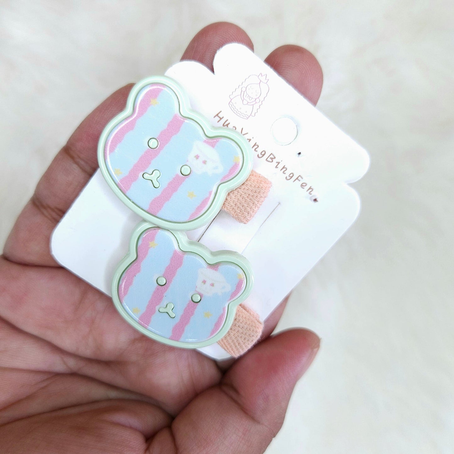 Cartoon bear-shaped hair clip held in a hand with a white background