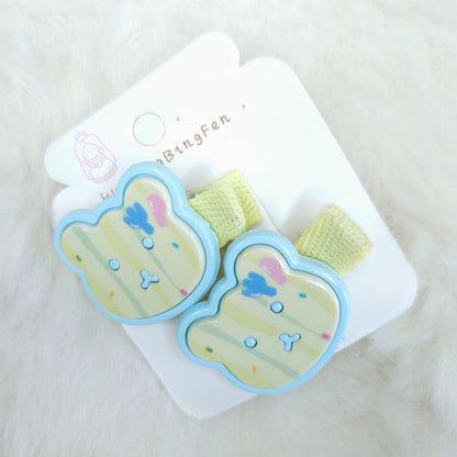 Pair of cartoon-themed hair clips on a white card with a soft white background