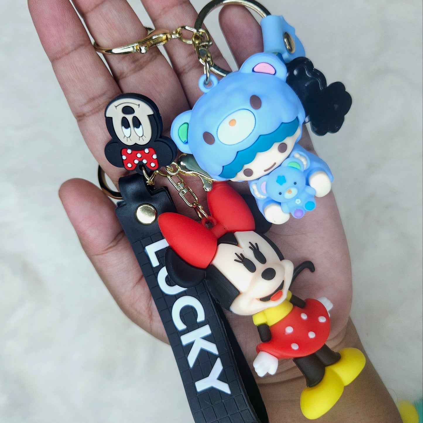 Hand holding a keychain with cartoon character charms and a visible brand name.