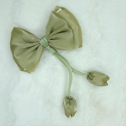 Close-up of a sheer olive green fabric bow with two pale purple fabric tulip buds dangling from a green stem.