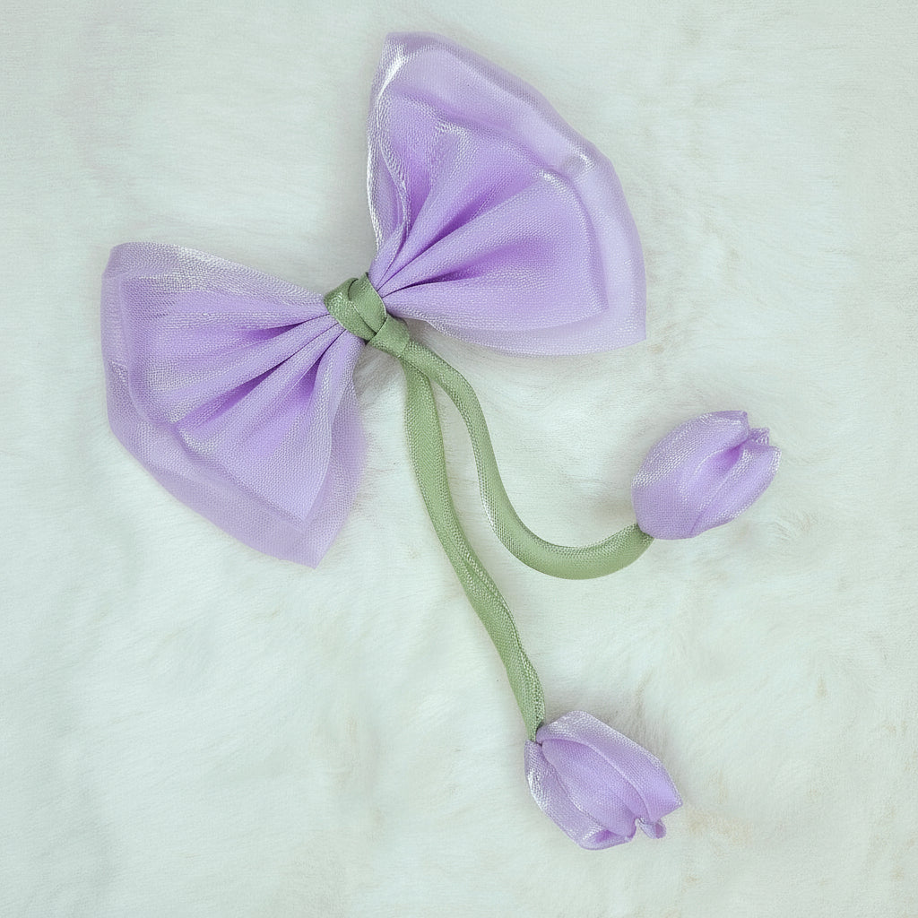 Close-up of a sheer lavender fabric bow with two pale purple fabric tulip buds dangling from a green stem.