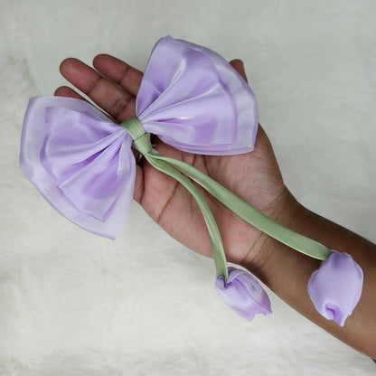 Close-up of a sheer lavender fabric bow with two pale purple fabric tulip buds dangling from a green stem.