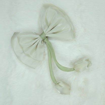 Close-up of a sheer cream fabric bow with two cream fabric tulip buds dangling from a green stem.
