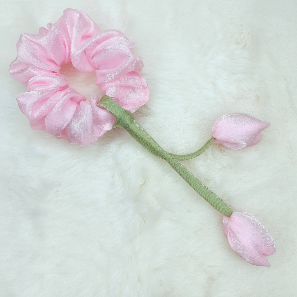 Elegant pink tulip scrunchie made of sheer fabric with decorative flower accents.