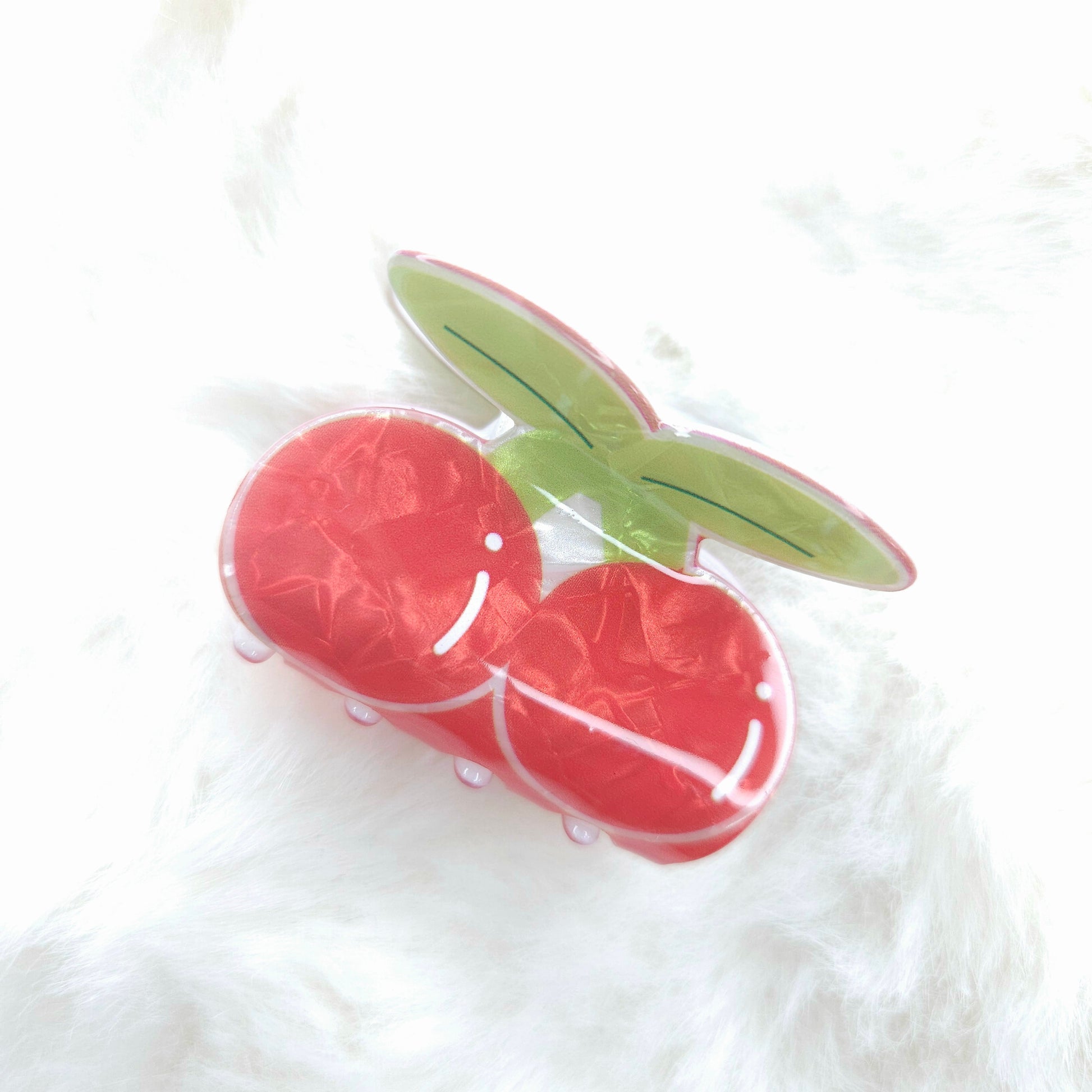 Red fruit-shaped hair claw with a green leaf on a white background