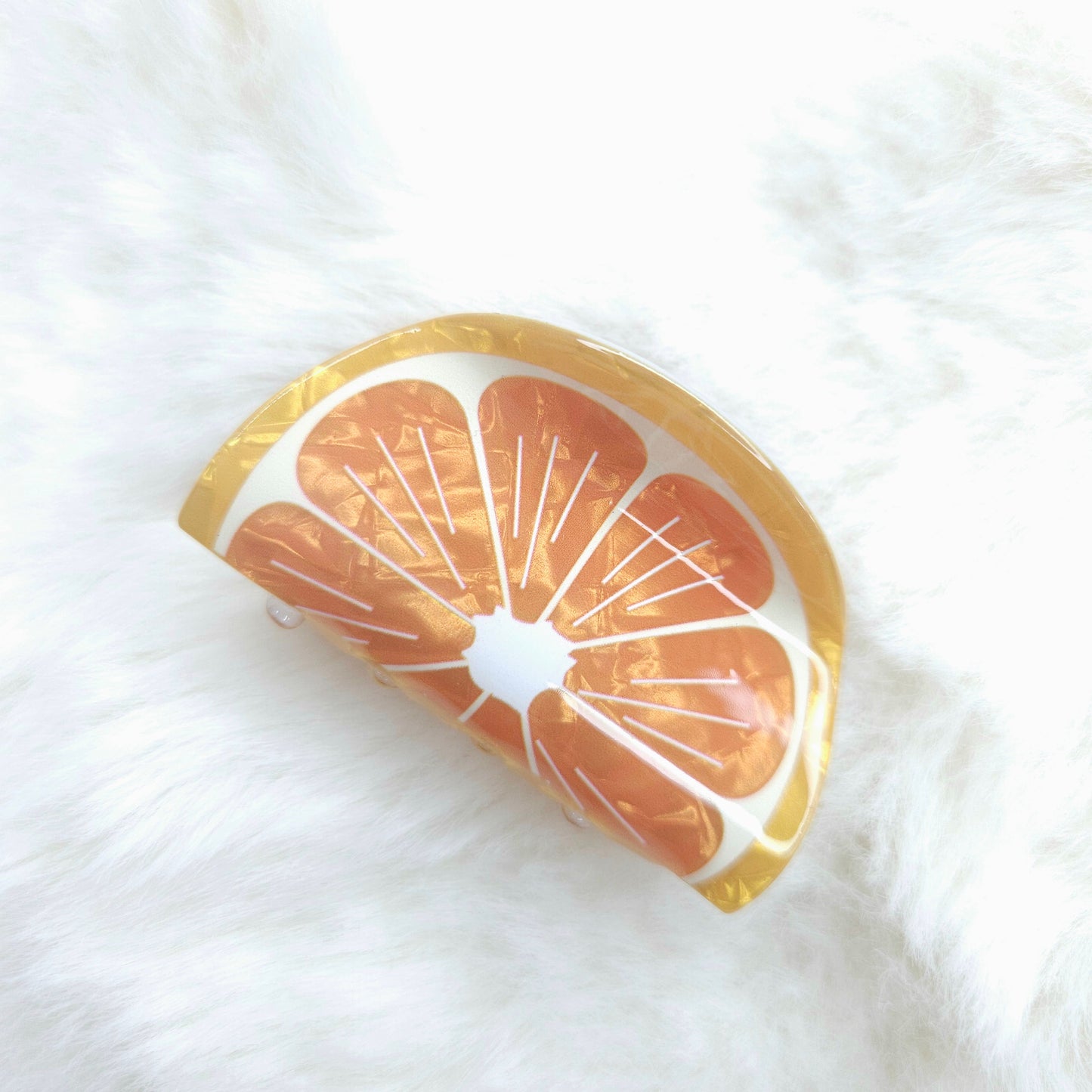 Grapefruit slice-shaped hair claw on a white background