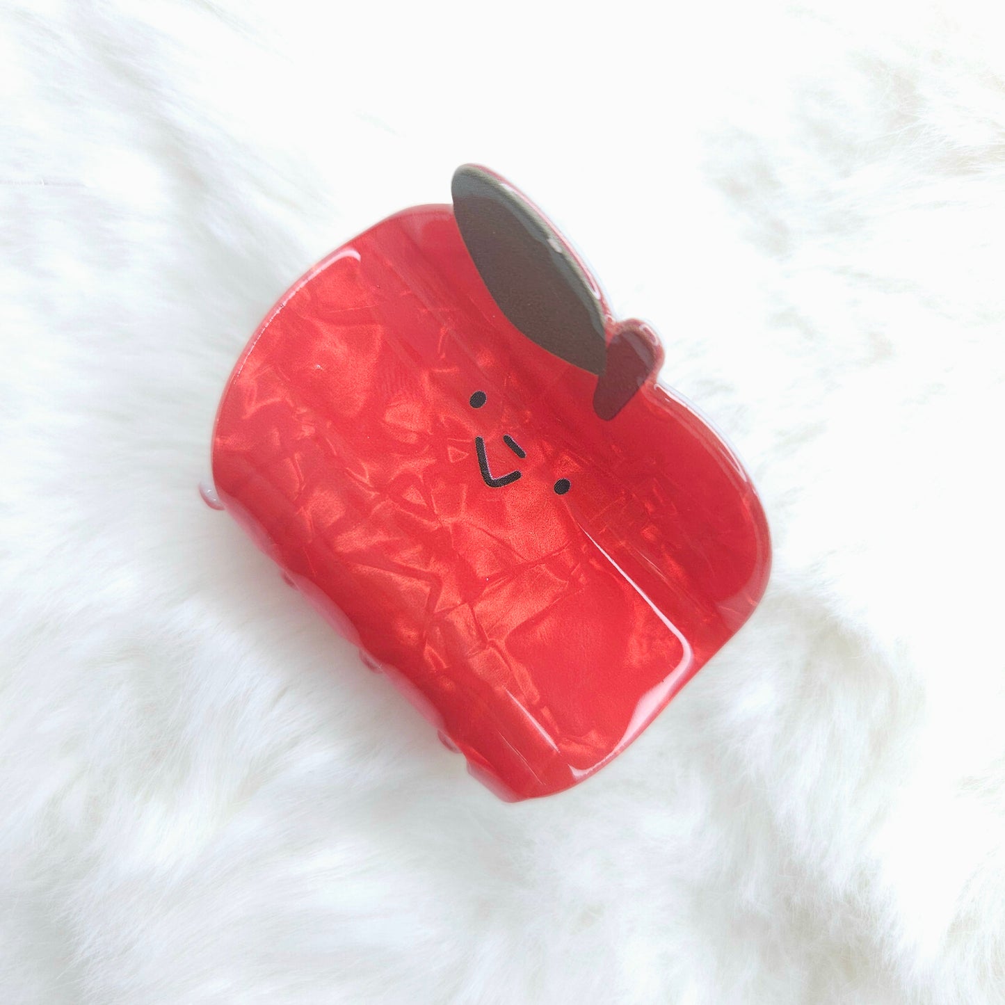 Red watermilon-shaped hair claw with a face on a white background