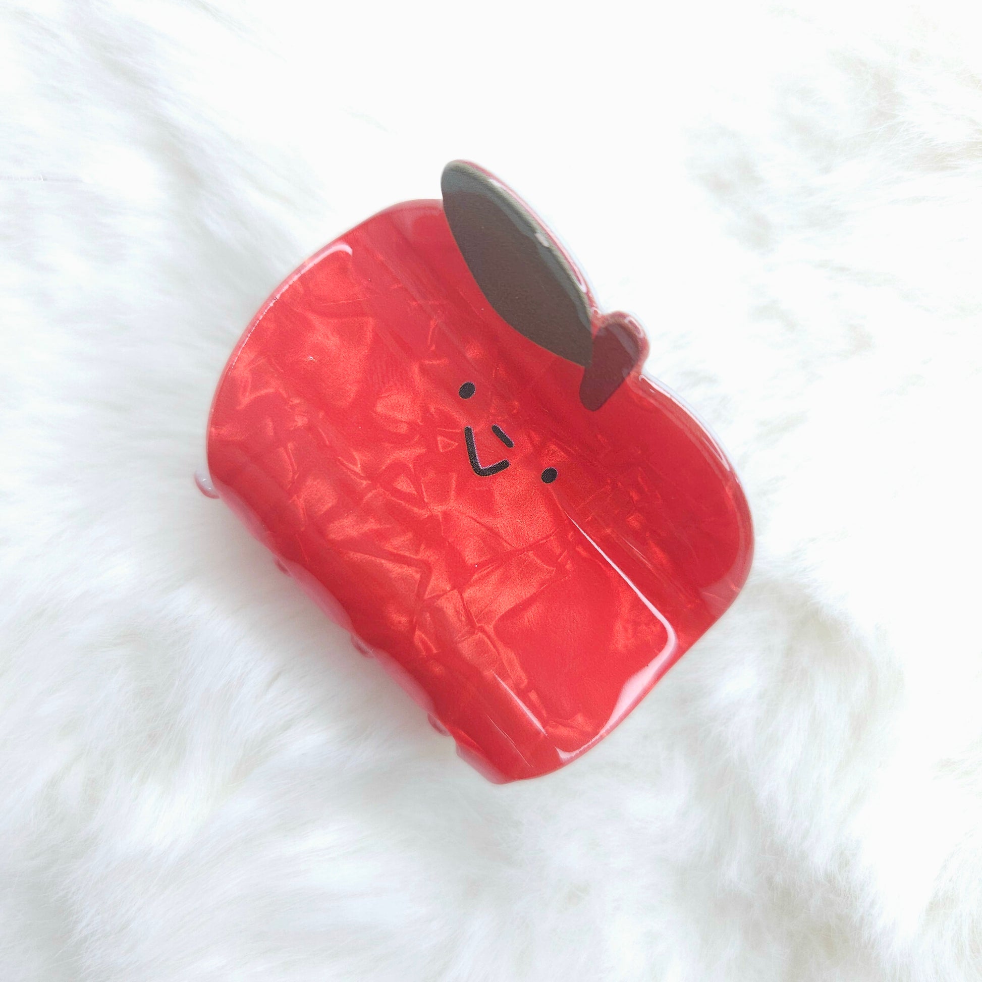 Red watermilon-shaped hair claw with a face on a white background