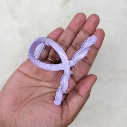Hand holding a purple hair clip against a plain background
