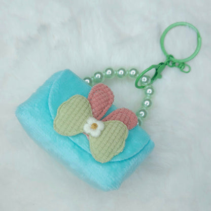 Small turquoise pouch with a pink and green butterfly charm on a white background