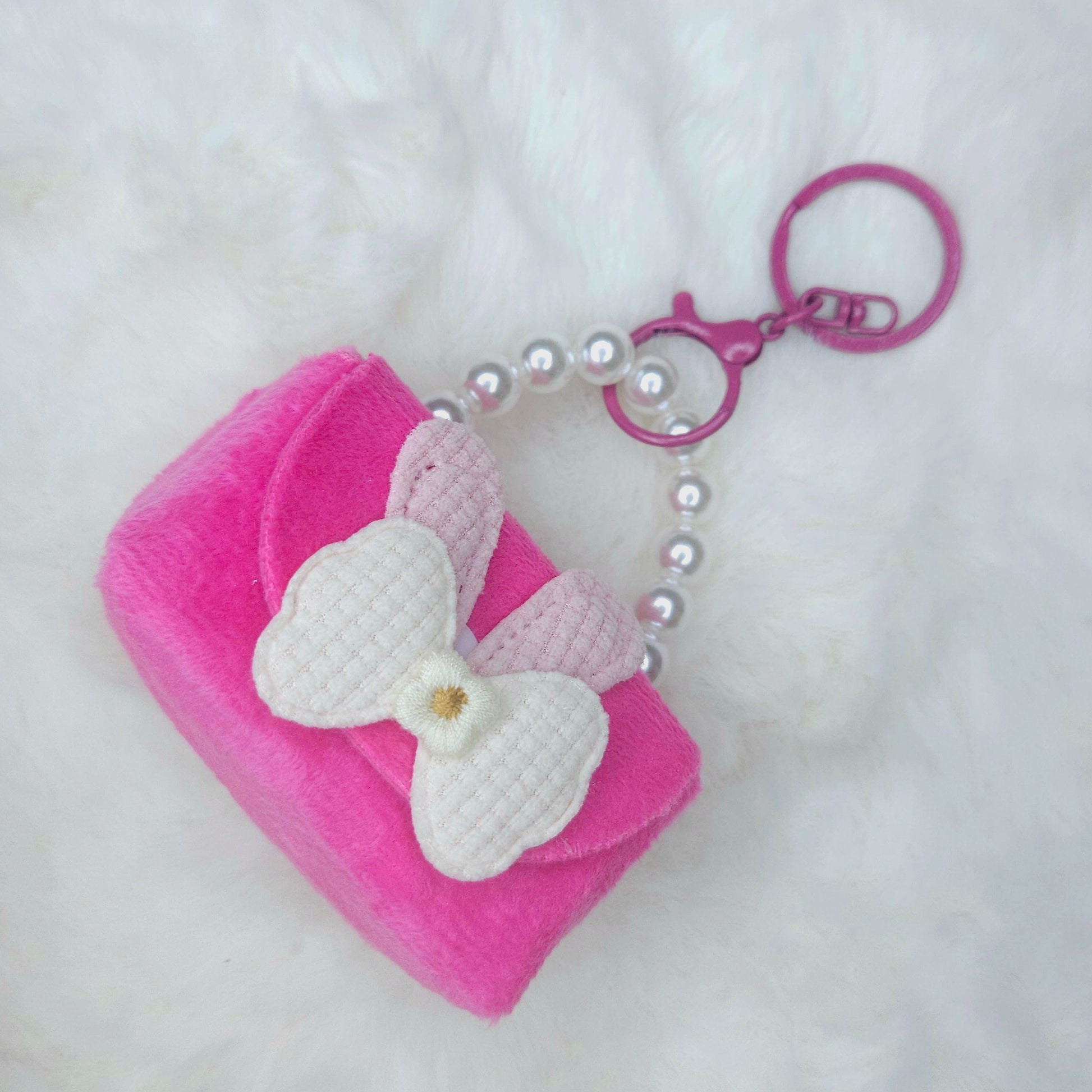 Pink pouch with a white bow and pearl chain on a white background