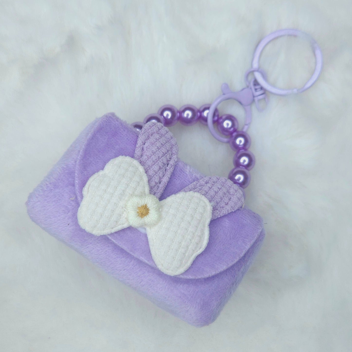 Purple keychain with a white bow on a light gray background