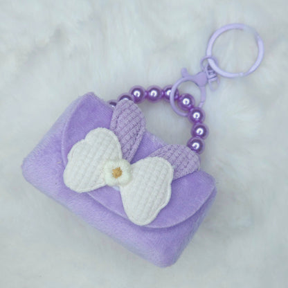Purple keychain with a white bow on a light gray background