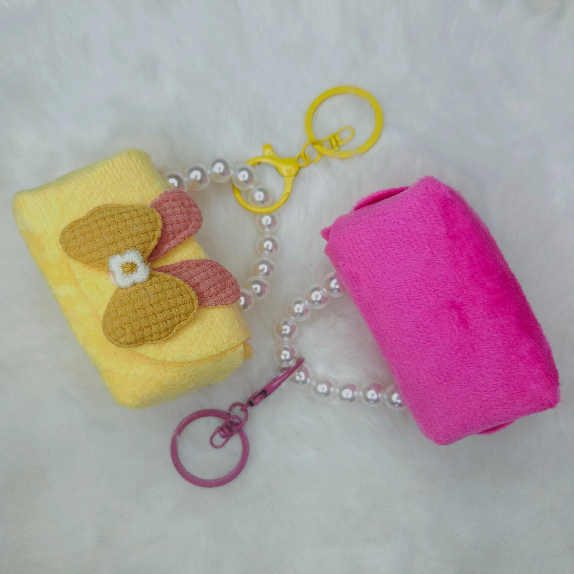 Yellow and pink keychain with a pearl chain on a light gray background