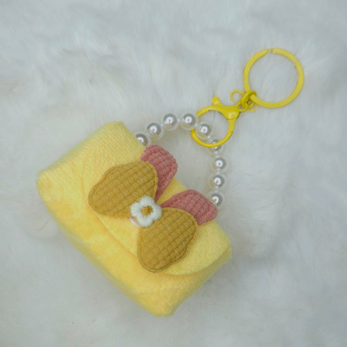 Yellow keychain with a decorative bow on a light gray background