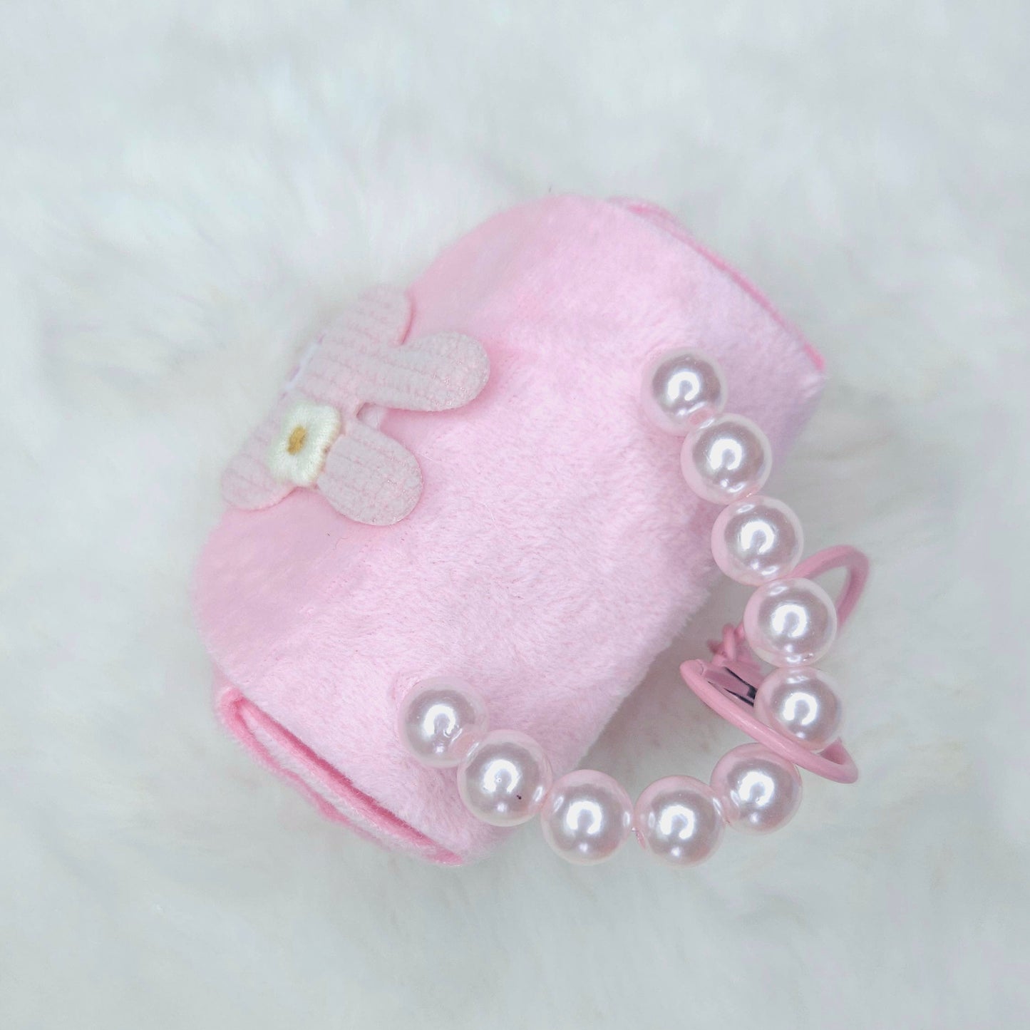 Pink pet accessory with pearl details on a light gray background