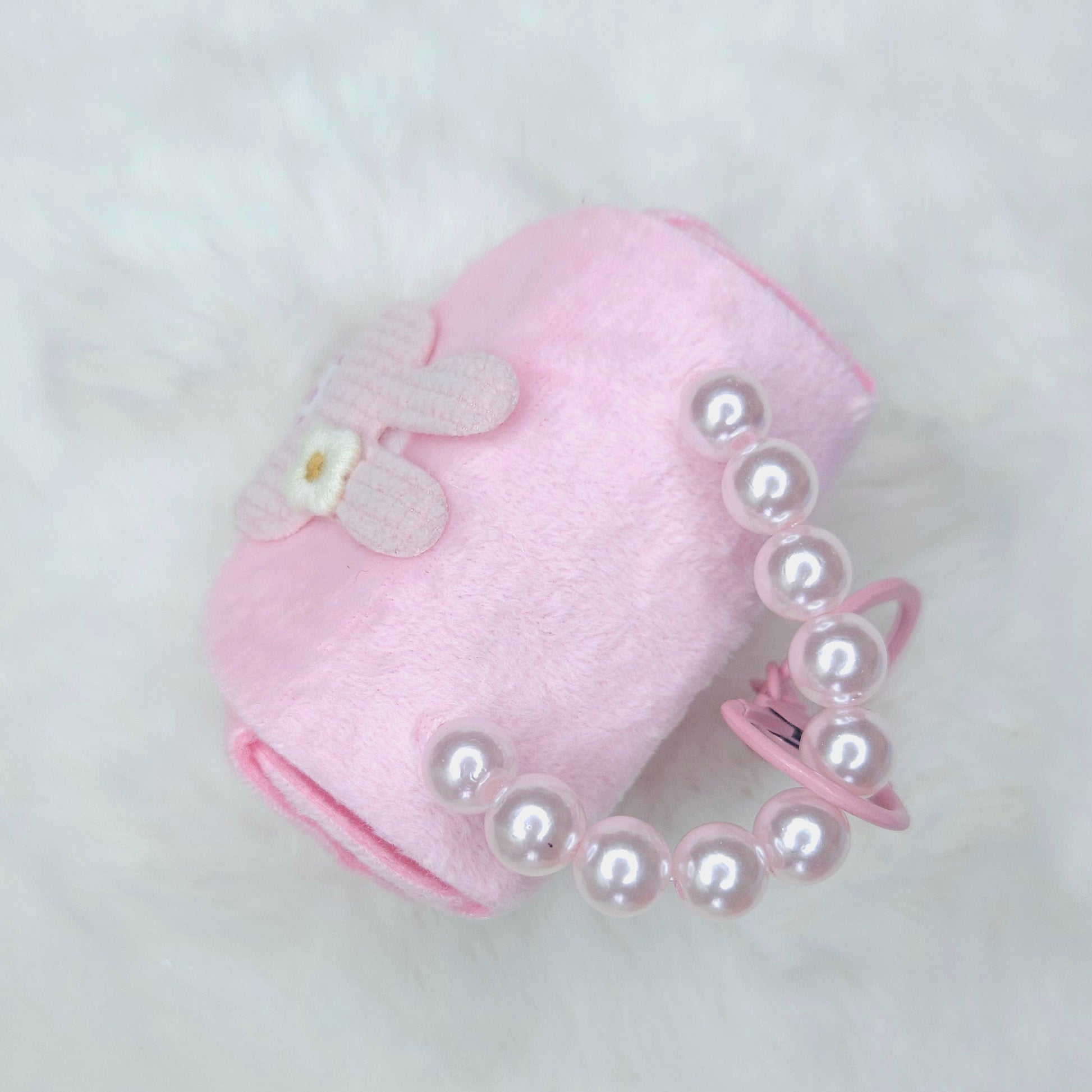 Pink pet accessory with pearl details on a light gray background