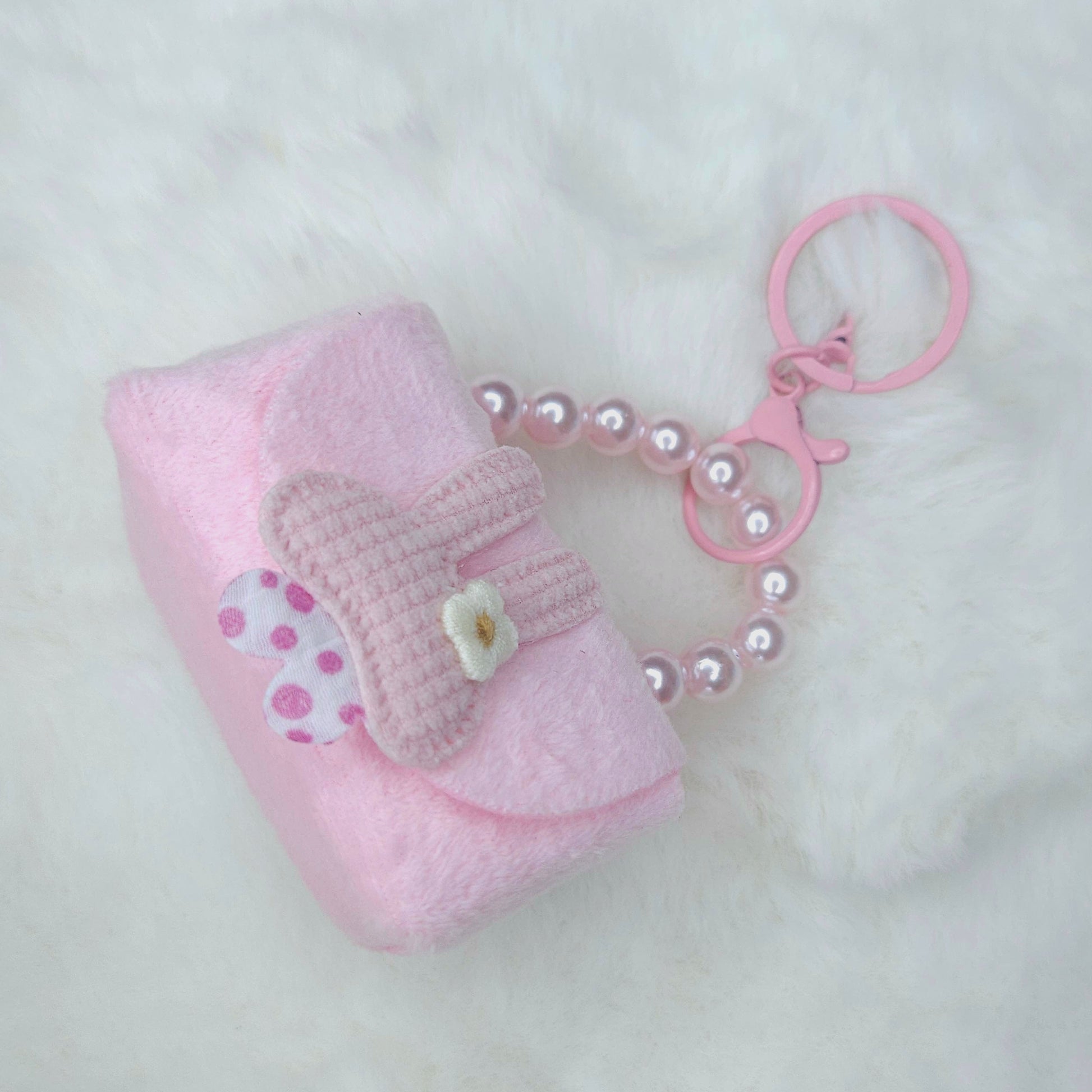 Pink baby bootie keychain with a pearl chain on a white background