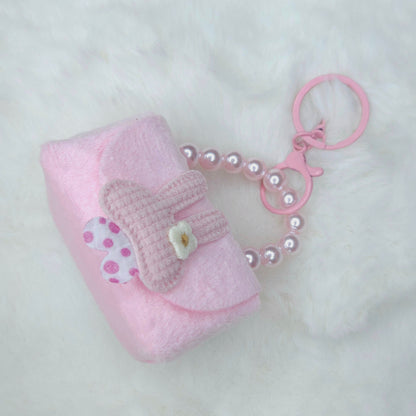 Pink baby bootie keychain with a pearl chain on a white background