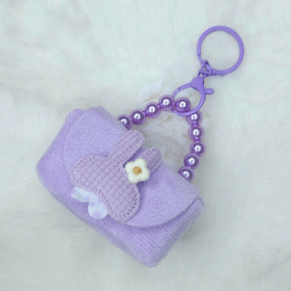 Purple keychain with a small pouch and flower decoration on a light gray background